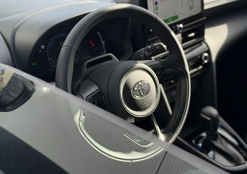 Vue rapprochée du volant multifonctions en cuir et de la console centrale du Toyota Yaris Cross 1.5 Hybrid 130 BVA Design.
