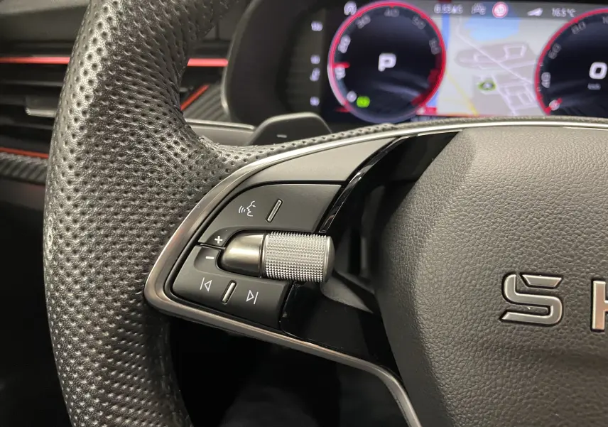 Gros plan sur la partie gauche du volant perforé d’une Skoda Scala 2025 avec commandes audio et tableau de bord numérique.