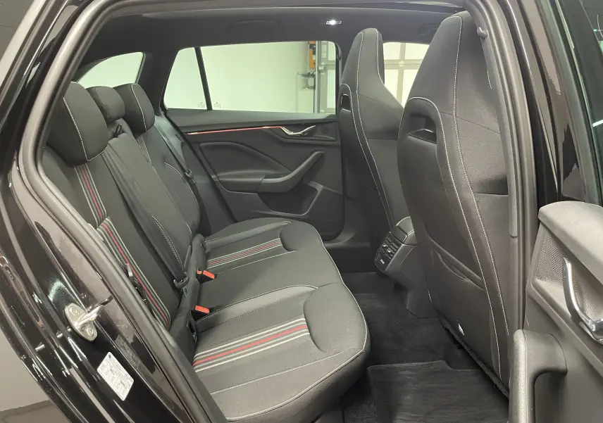 Vue intérieure côté gauche sur les sièges arrière noirs avec surpiqûres blanches et bandes rouges du Skoda Scala Monte-Carlo 2025.