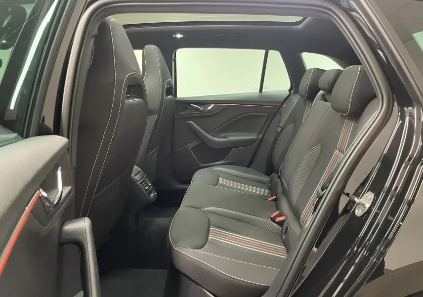 Vue intérieure côté droit sur les sièges arrière noirs avec surpiqûres blanches et bandes rouges du Skoda Scala Monte-Carlo 2025.