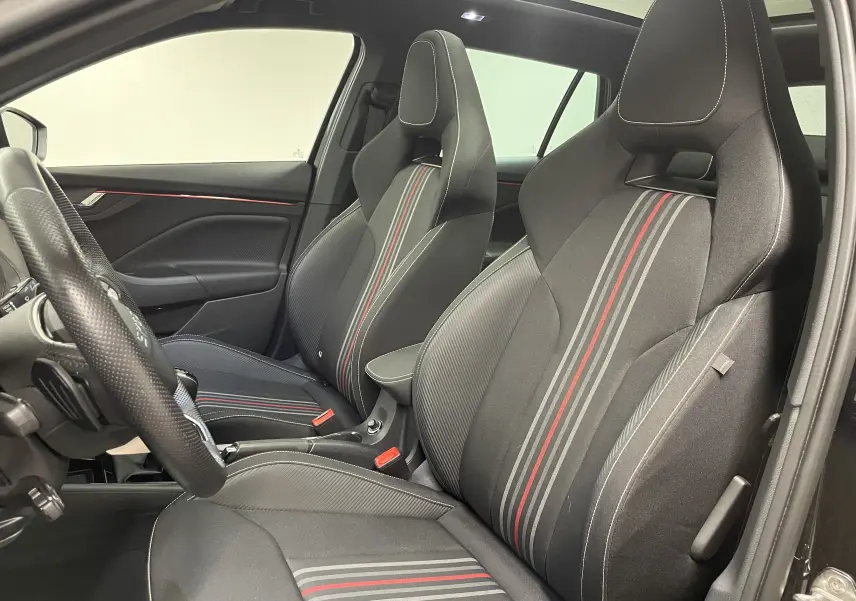 Vue intérieure côté conducteur de la Skoda Scala 1.5 TSI Monte-Carlo 2025, sièges sport noirs avec bandes rouges et grises.