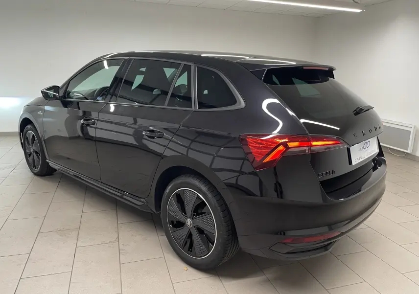 Vue 3/4 arrière droite d’une Skoda Scala 2025 Noir Magic avec feux arrière allumés et jantes spécifiques Monte-Carlo.