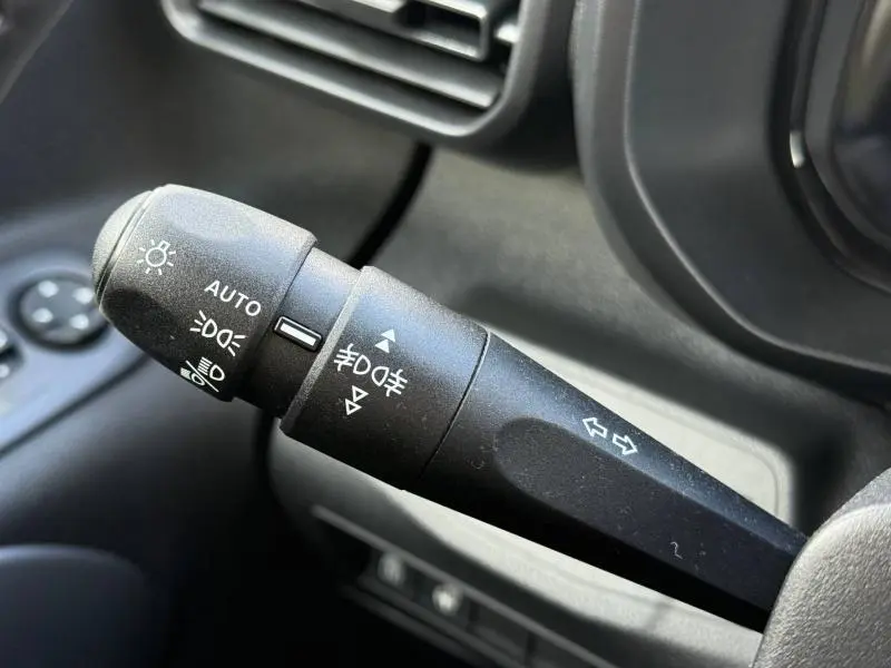Gros plan sur le commodo gauche noir du Citroën Berlingo 2025, avec commandes d’éclairage et clignotants visibles.