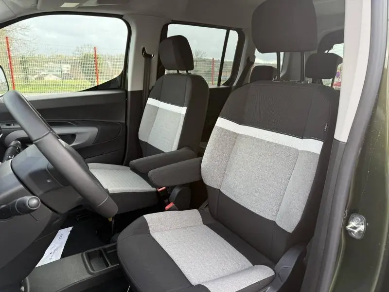 Vue intérieure côté conducteur du Citroën Berlingo 2025 avec sièges bicolores gris et accoudoir central.