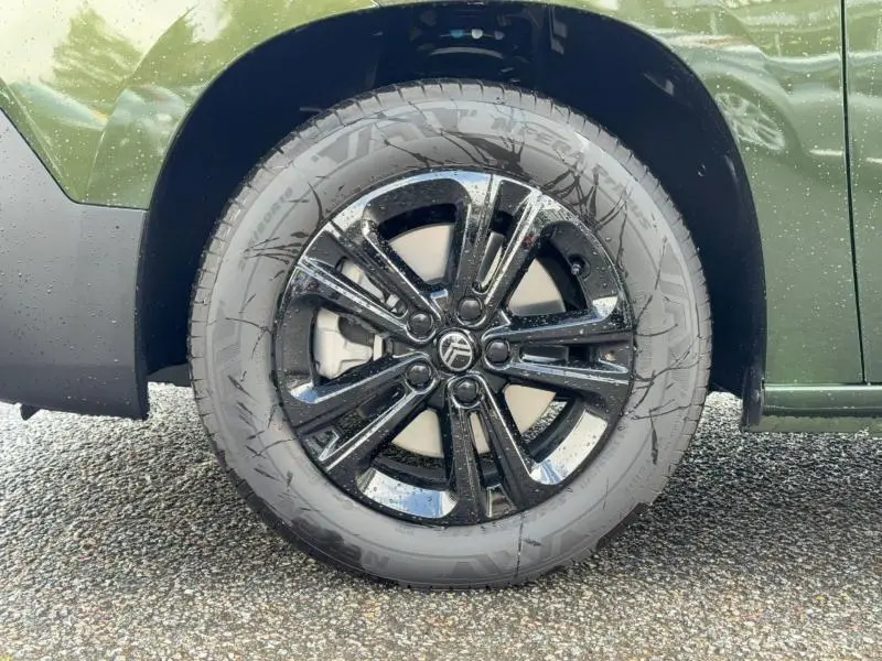 Gros plan sur la roue avant gauche avec jante noire brillante du Citroën Berlingo Sirkka Green 2025.