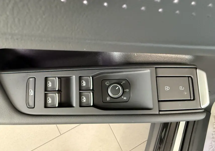 Vue rapprochée des commandes de lève-vitres et rétroviseurs sur la porte côté gauche d’un Volkswagen T-Roc noir intense.