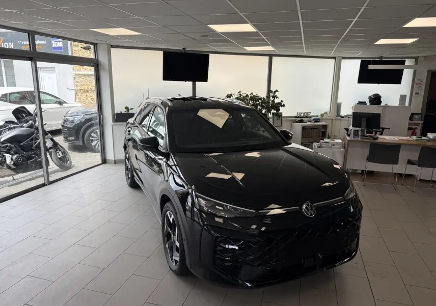 Volkswagen T-Roc R-Line noir intense vu en 3/4 avant droit dans un showroom lumineux avec jantes noires.