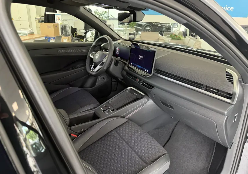 Vue intérieure côté conducteur du Volkswagen T-Roc R-Line noir intense 2026, avec tableau de bord numérique et sièges en tissu noir.