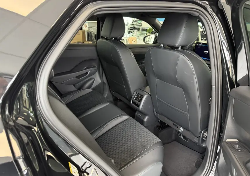 Vue intérieure côté arrière droit du Volkswagen T-Roc R-Line noir intense 2026, montrant les sièges en cuir et tissu avec console centrale.