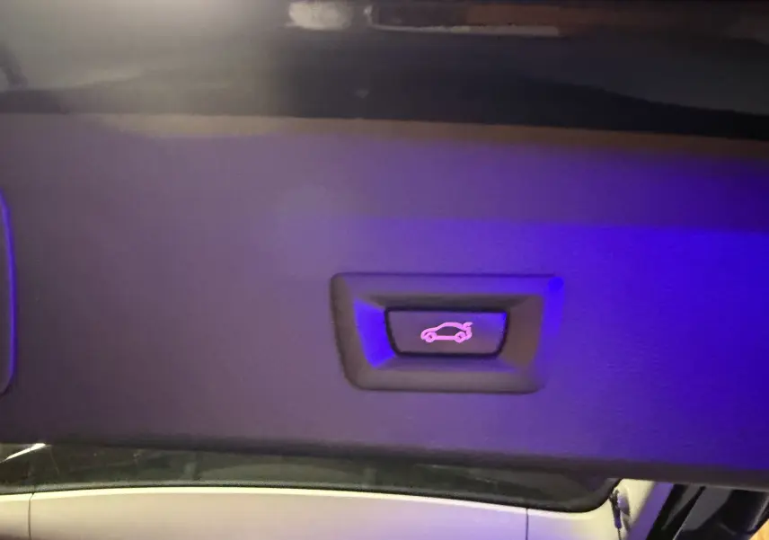 Bouton d'ouverture électrique du hayon intérieur éclairé en violet, sur BMW X1 noir (F48) 2019, vue en gros plan.