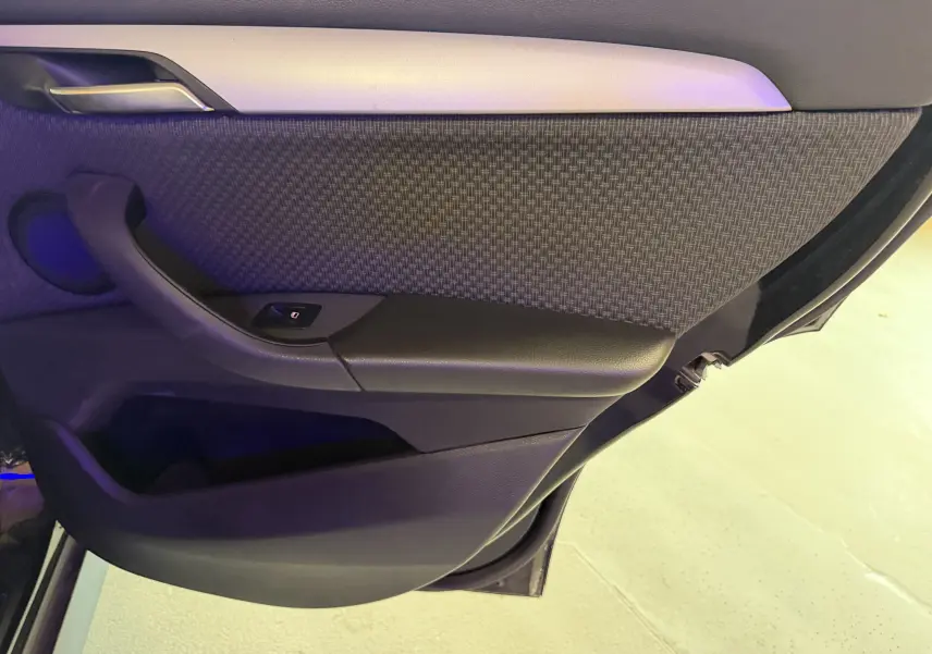 Détail de la porte arrière droite du BMW X1 noir 2019, montrant le revêtement tissu et plastique avec commande de vitre.