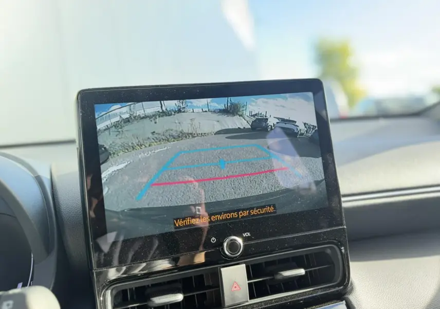 Écran tactile intérieur montrant la caméra de recul d'une Toyota Yaris Cross gris Atlas, tableau de bord noir visible.