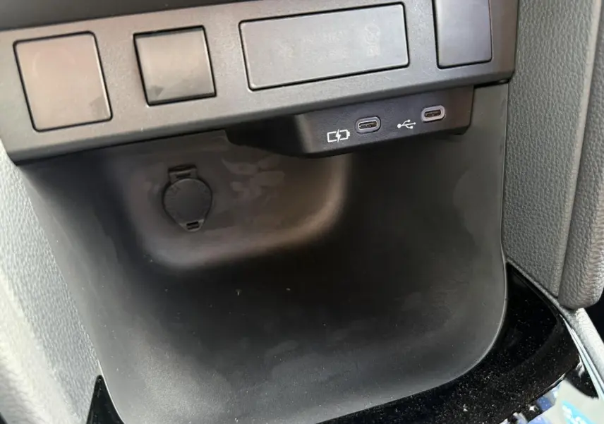 Gros plan intérieur sur les deux ports USB-C et prise 12V noirs de la Toyota Yaris Cross 2026.