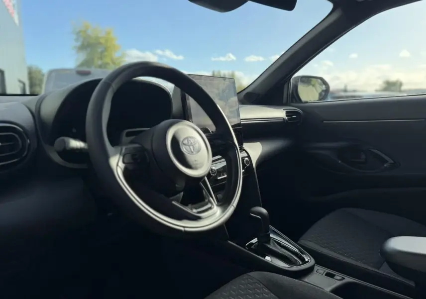 Vue intérieure côté conducteur de la Toyota Yaris Cross 2026, volant multifonctions et écran tactile central visibles.
