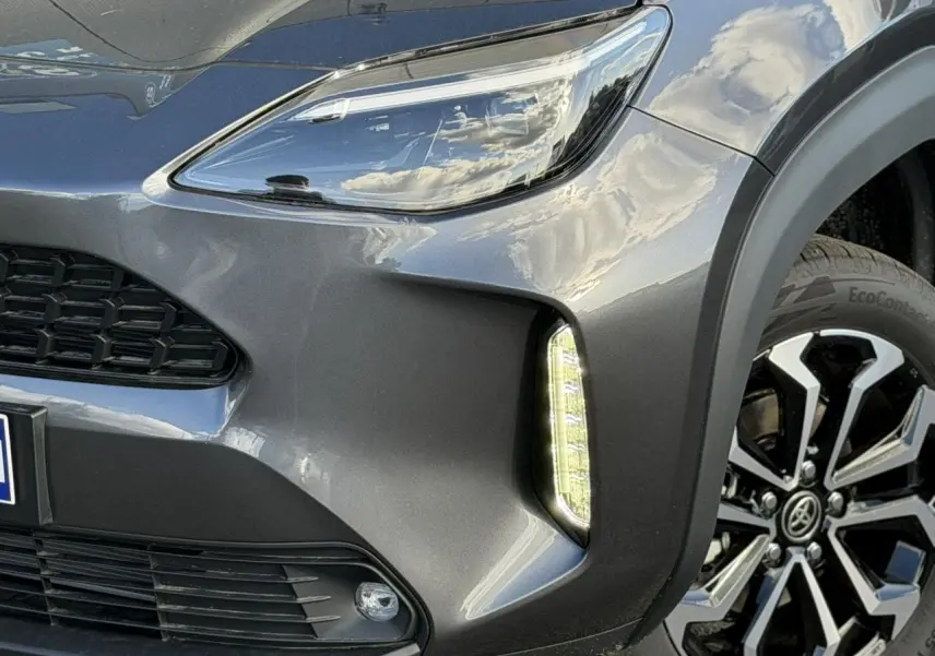 Gros plan sur l'avant droit gris Atlas du Toyota Yaris Cross 2026, mettant en valeur le phare LED et la jante alliage 17 pouces.