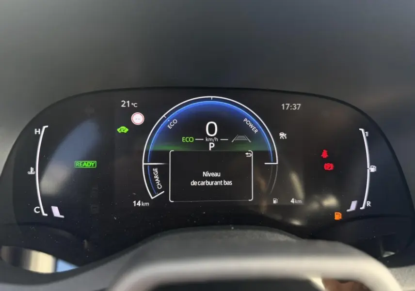 Vue rapprochée du tableau de bord numérique de la Toyota Yaris Cross 2026, affichant un avertissement de niveau de carburant bas.