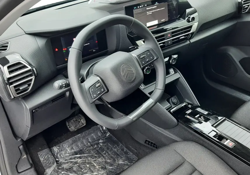 Vue intérieure côté conducteur de la Citroën C4 hybride 2026, tableau de bord moderne avec écran tactile et volant multifonction noir.