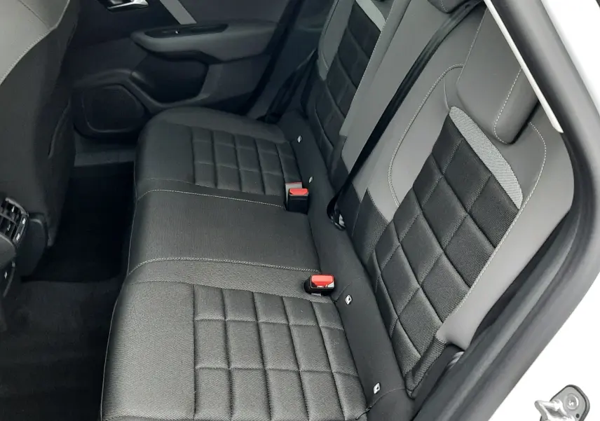 Vue intérieure arrière droite des sièges arrière gris foncé et clairs de la Citroën C4 blanche 2026 hybride.