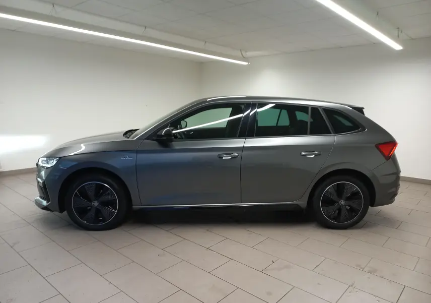 Profil droit d'une Skoda Scala 1.5 TSI 150 DSG7 Monte-Carlo en gris graphite métallisé, roues noires distinctives.