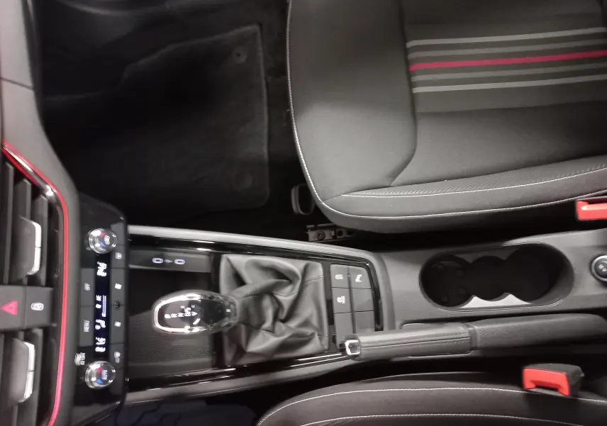 Vue plongeante sur la console centrale et le siège avant droit de la Skoda Scala 1.5 TSI Monte-Carlo avec surpiqûres rouges.