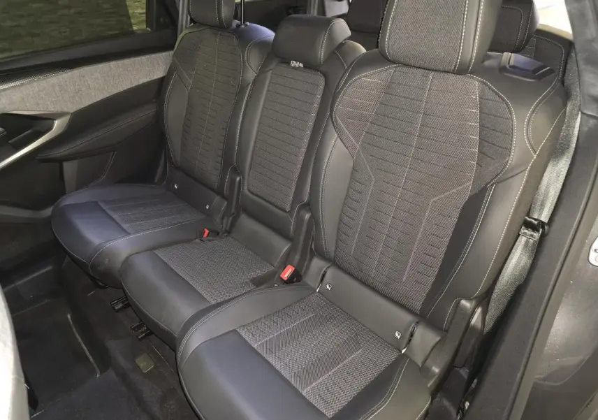 Vue intérieure côté droit sur la banquette arrière 3 places en tissu et cuir noir du Peugeot 5008 gris hybride 2025.
