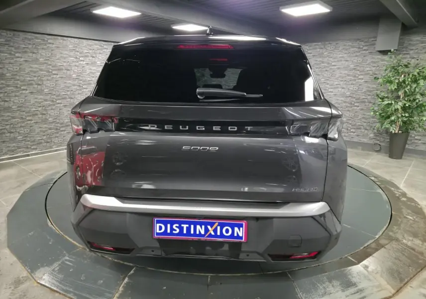 Vue arrière d'un Peugeot 5008 gris métallisé avec bandeau noir laqué et feux arrière 3 griffes LED en intérieur showroom.