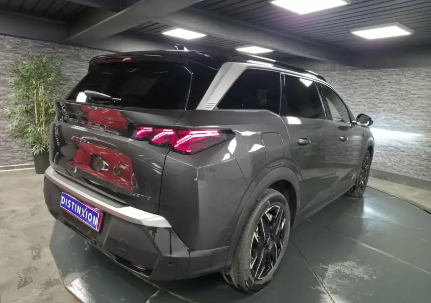 Vue 3/4 arrière droit du Peugeot 5008 gris métallisé avec feux arrière LED 3 griffes et jantes alliage noires.