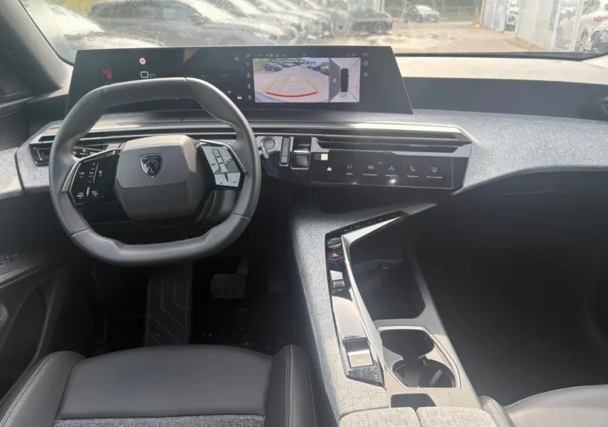 Intérieur du Peugeot 5008 Hybrid 2025 vu de face, tableau de bord moderne avec écran tactile et volant compact noir.
