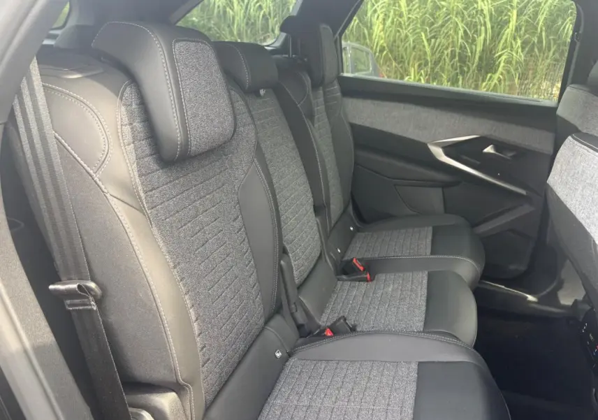 Vue côté droit de la banquette arrière du Peugeot 5008 Hybrid 2025, avec sellerie tissu gris et cuir noir.