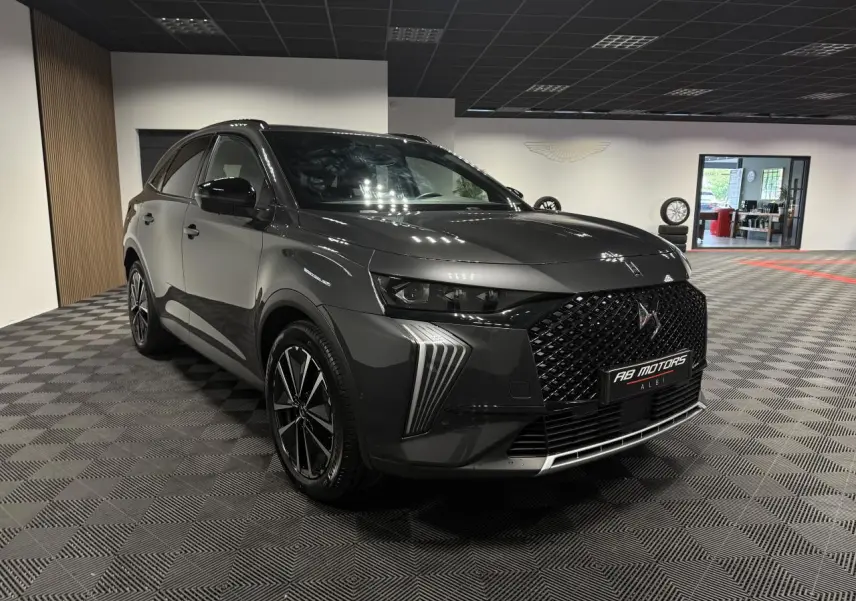 DS7 Crossback gris en 3/4 avant droit, avec calandre noire brillante et jantes alliage 19 pouces dans un showroom.