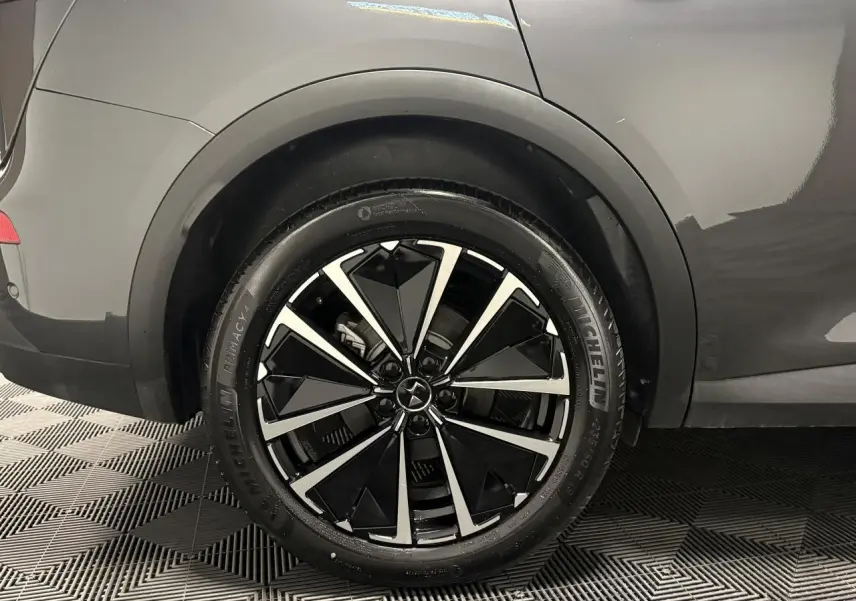 Gros plan sur la roue arrière droite d’un DS7 Crossback gris avec jante alliage noire et argentée au design géométrique.