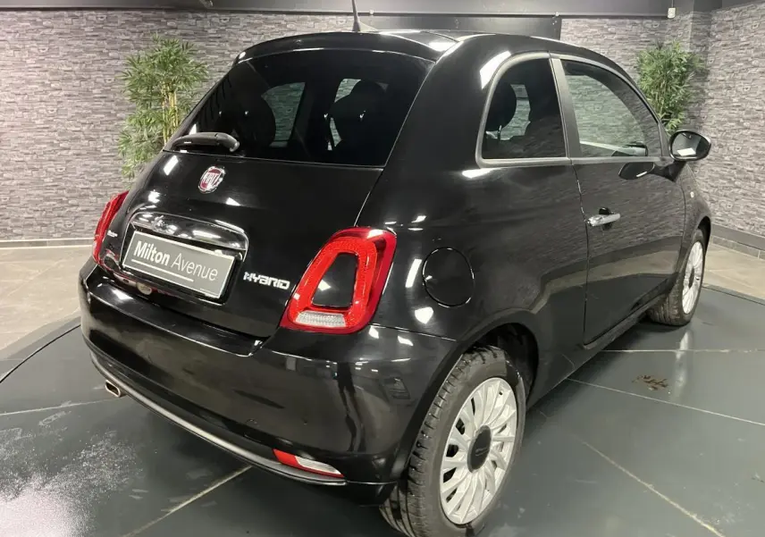 Vue 3/4 arrière droite d'une Fiat 500 noire hybride 2023 avec feux arrière LED et jantes alliage claires.