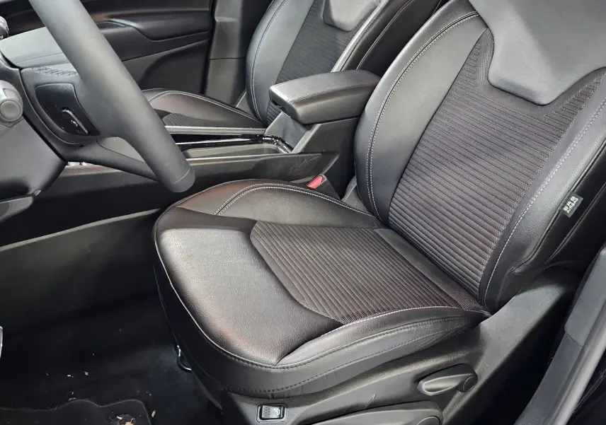 Vue rapprochée du siège conducteur noir en cuir et tissu du Jeep Compass 2023 avec accoudoir central et volant partiel.