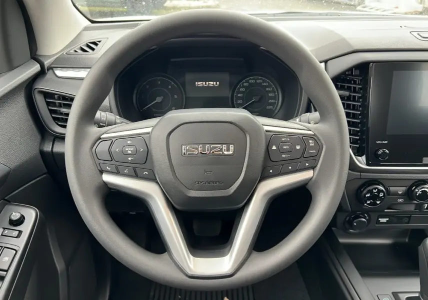 Vue intérieure centrée sur le volant multifonctions gris d'un Isuzu D-MAX 2026 avec tableau de bord et écran tactile.