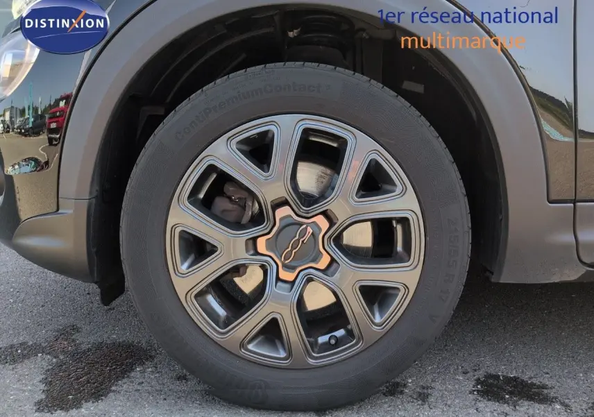 Gros plan sur la roue avant gauche de la Fiat 500X noire avec jante alu bronze du Pack Style.