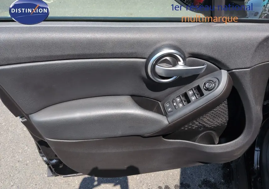 Gros plan sur la porte avant gauche noire avec commandes électriques et poignée argentée du Fiat 500X 2018.