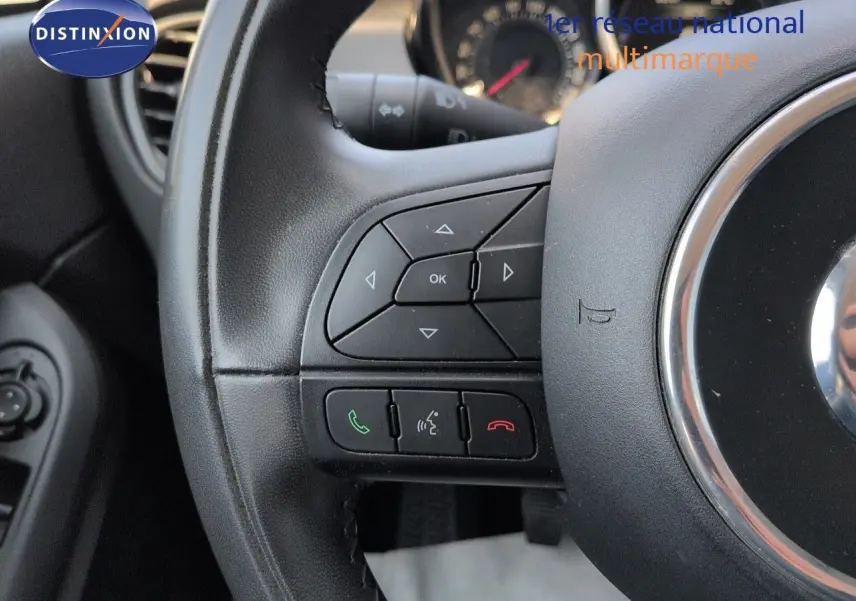 Gros plan sur le volant cuir multifonction noir du Fiat 500X avec commandes audio et téléphone intégrées.