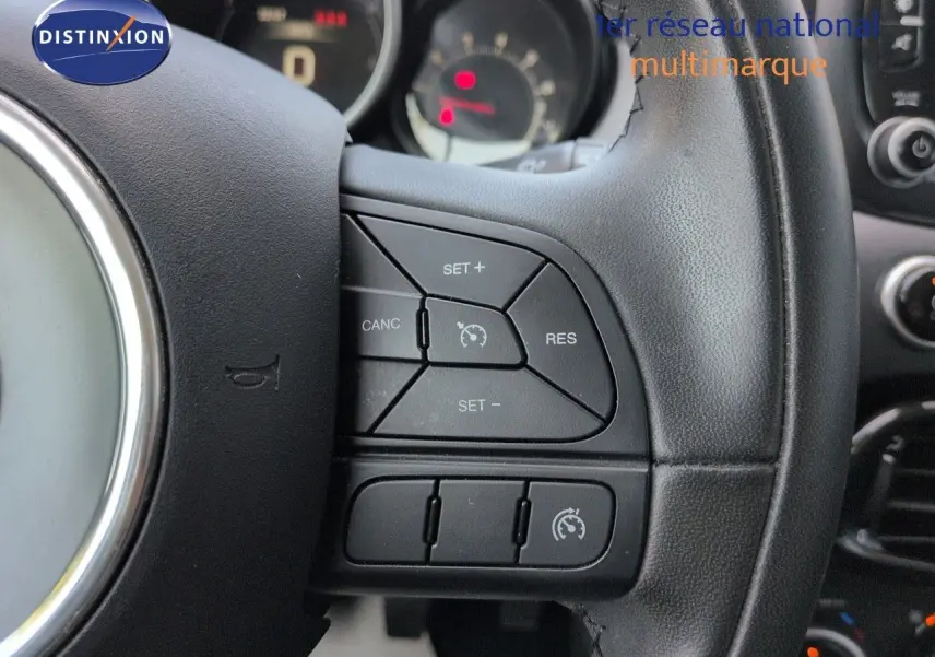 Gros plan sur le volant cuir noir multifonction du Fiat 500X 2018 avec commandes de régulateur de vitesse.