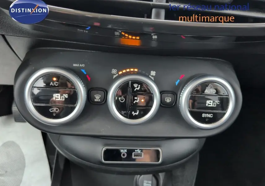 Gros plan sur la console centrale de la Fiat 500X 2018, montrant les commandes de climatisation bi-zone et prises audio.