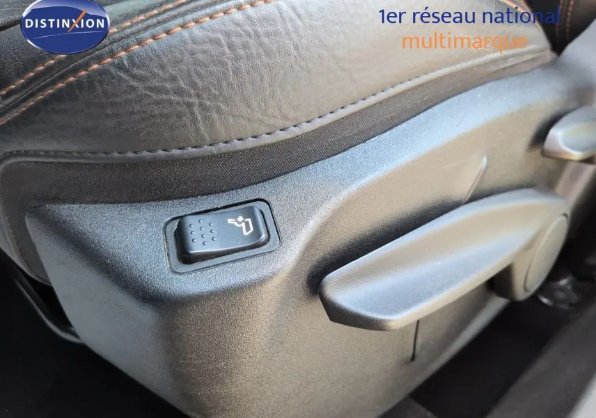 Gros plan sur la commande de réglage lombaire d’un siège en cuir noir avec surpiqûres orange du Fiat 500X.
