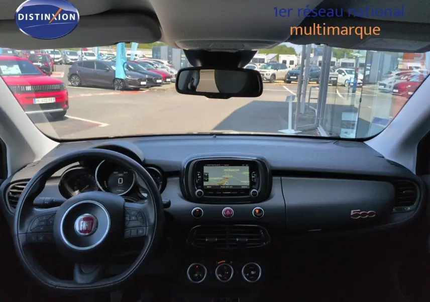 Vue intérieure du tableau de bord noir d'une Fiat 500X 2018 avec écran tactile et volant multifonction.