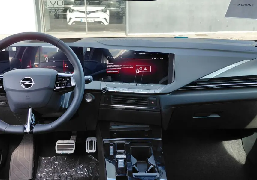 Vue intérieure avant de l’Opel Astra 2025 noire, mettant en valeur le tableau de bord numérique et la console centrale moderne.