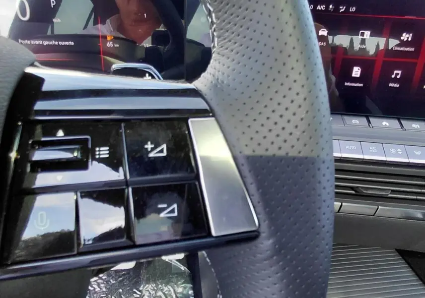 Gros plan sur le volant perforé et les commandes intégrées côté gauche de l’Opel Astra 2025 avec tableau de bord numérique.