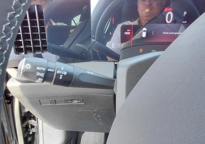 Gros plan sur la commande des feux et le tableau de bord numérique noir de l'Opel Astra 2025 Diesel, côté gauche.