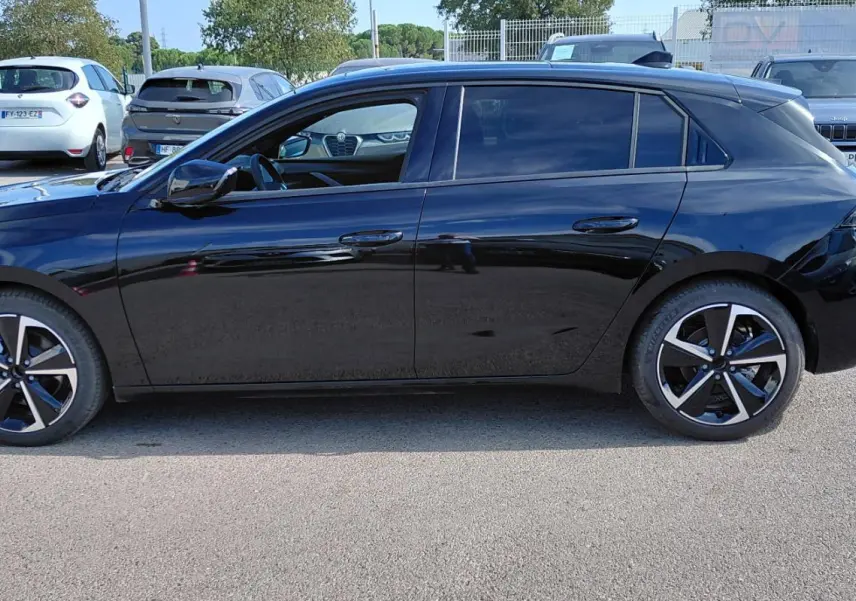 Opel Astra 2025 noire vue de profil côté gauche, avec jantes alliage bicolores et vitres teintées.
