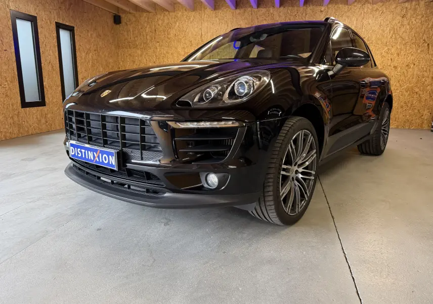 Vue 3/4 avant droite d’un Porsche Macan S noir brillant avec jantes alu 21 pouces et phares bi-xénon en intérieur bois.