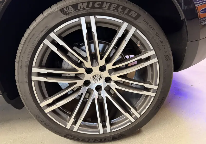 Gros plan sur la jante alu 21 pouces et pneu Michelin du côté arrière droit d'un Porsche Macan S noir.