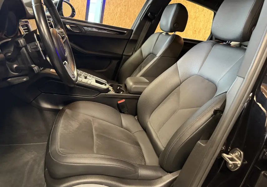 Vue intérieure côté conducteur du Porsche Macan S noir, mettant en valeur les sièges cuir et le volant multifonctions.