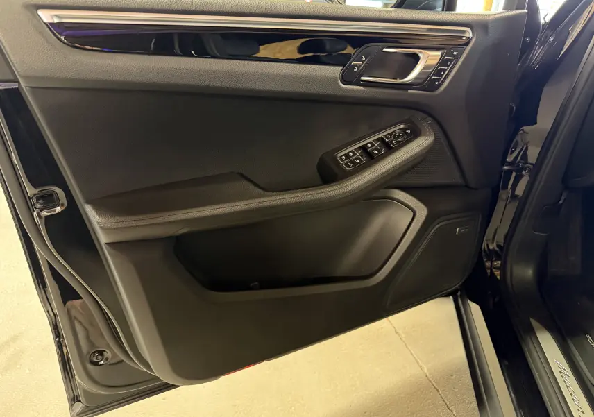 Vue rapprochée de la porte avant gauche noire du Porsche Macan S avec commandes électriques et finition intérieure noire.