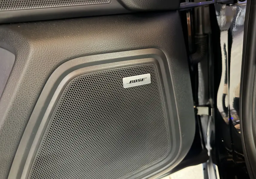 Gros plan sur l’enceinte Bose intégrée dans la porte intérieure noire du Porsche Macan S 3.0i.